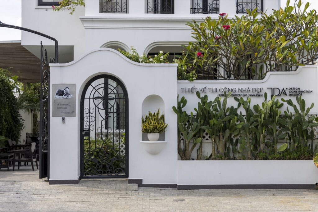 Cổng và tường rào biệt thự trắng với bồn cây xanh